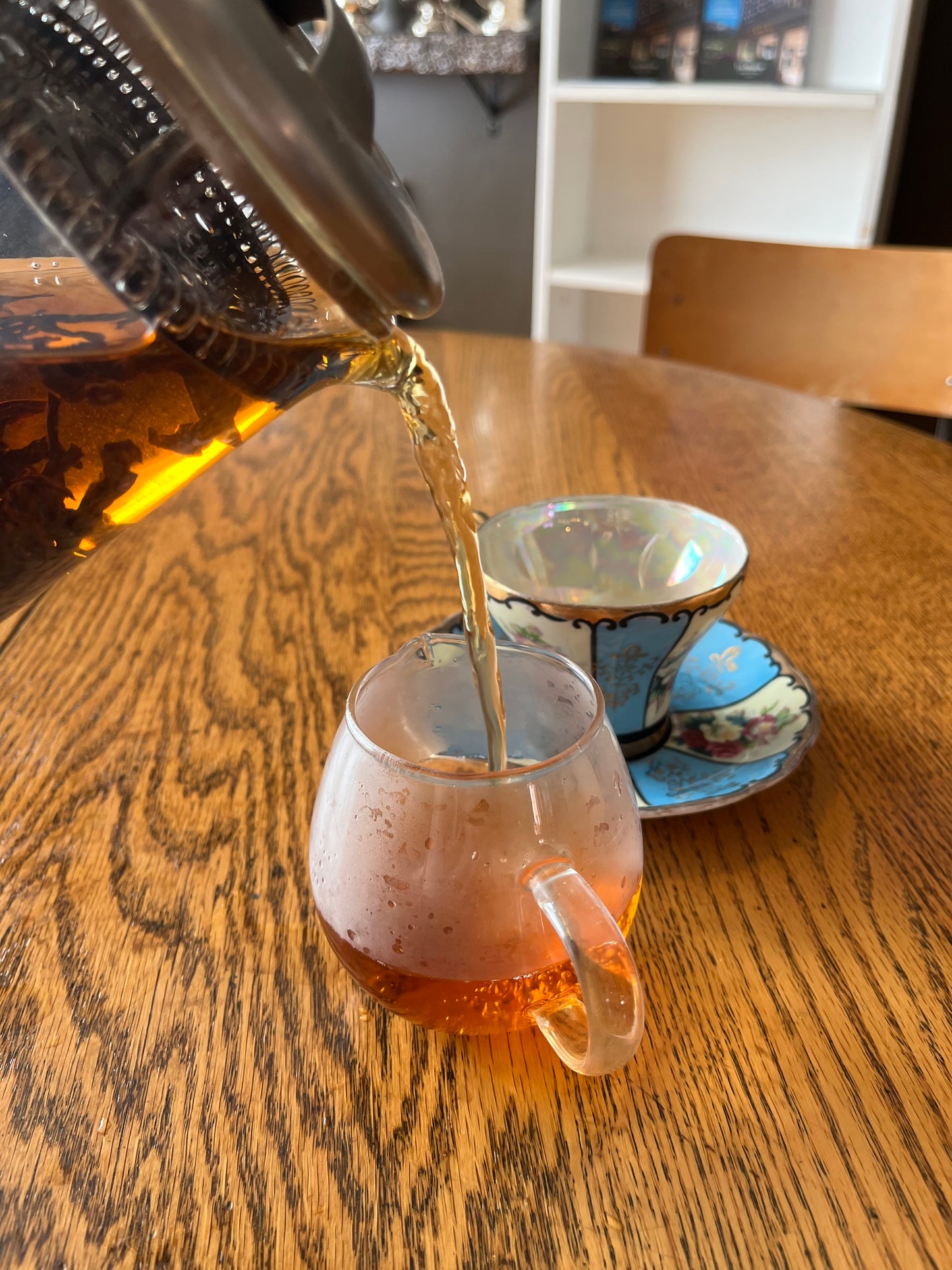 Close-up of a black tea being poured into a glass on a wooden table
