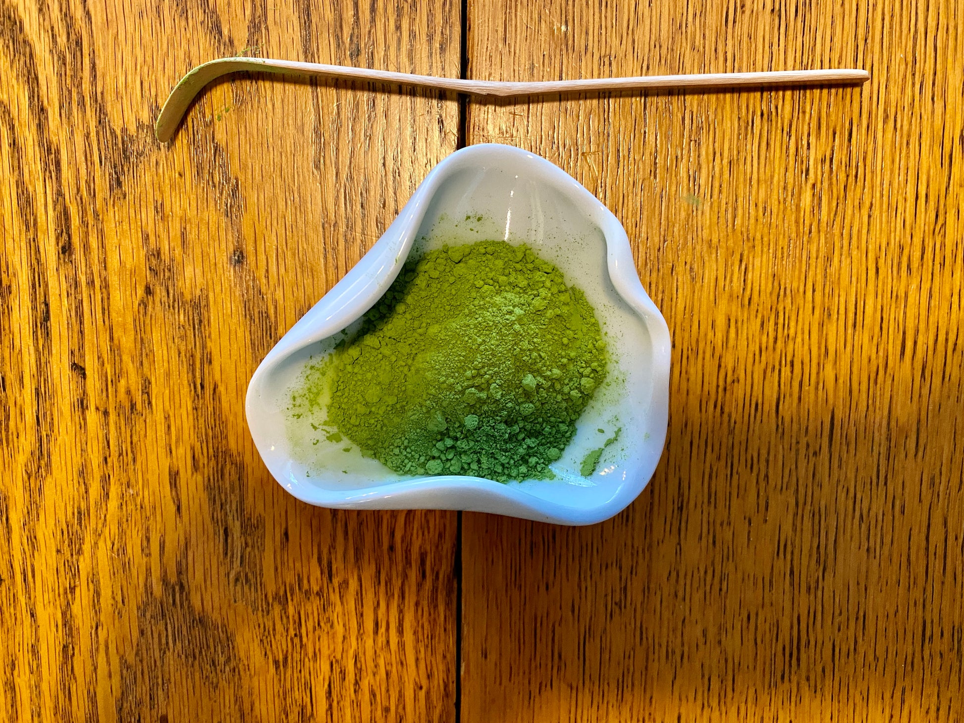 Ceremonial uji matcha powder on a wooden table in ceramic bowl