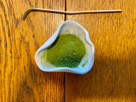 Ceremonial uji matcha powder on a wooden table in ceramic bowl