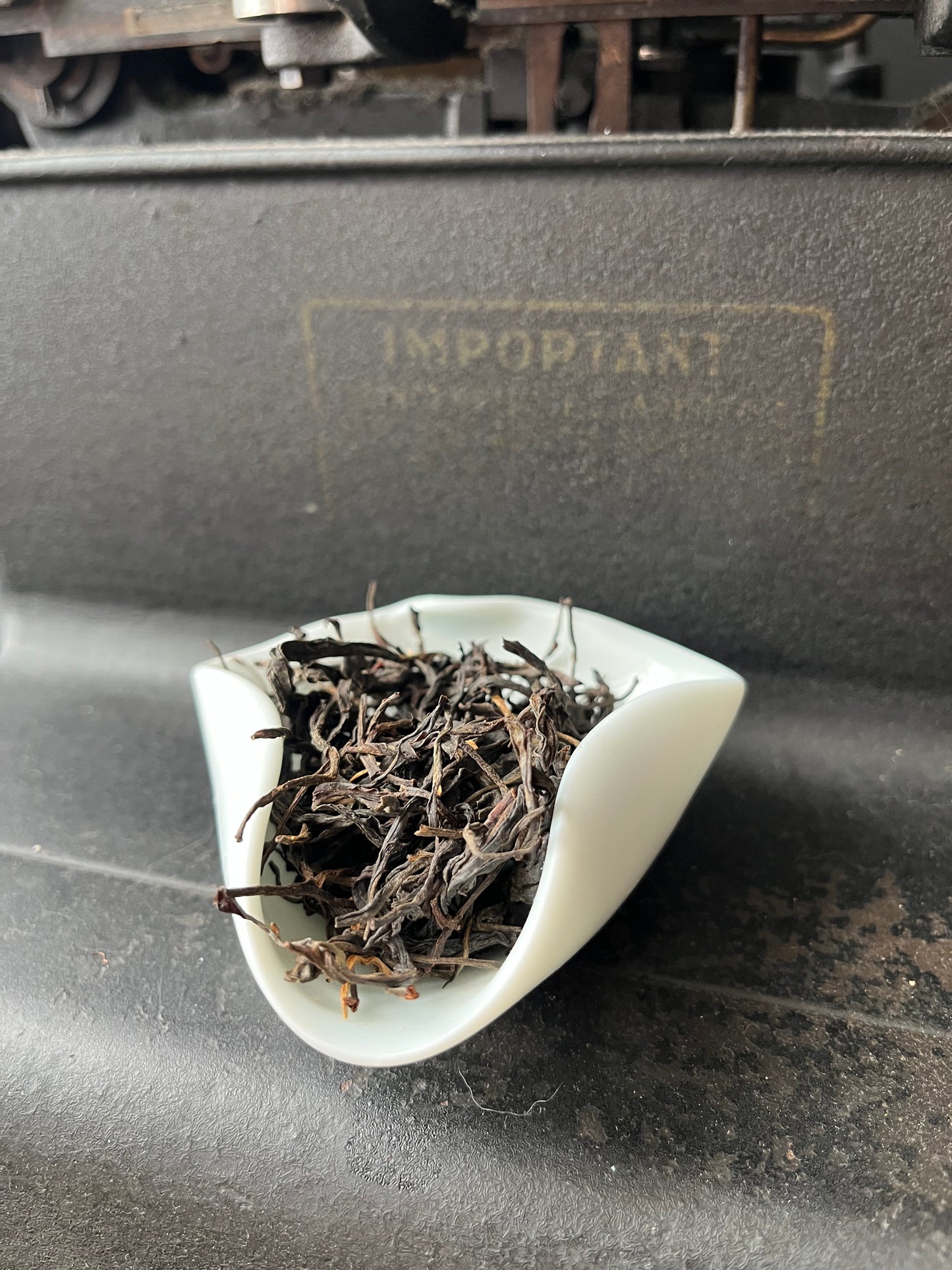 Dried black tea leaves inside, attached to a dark surface.