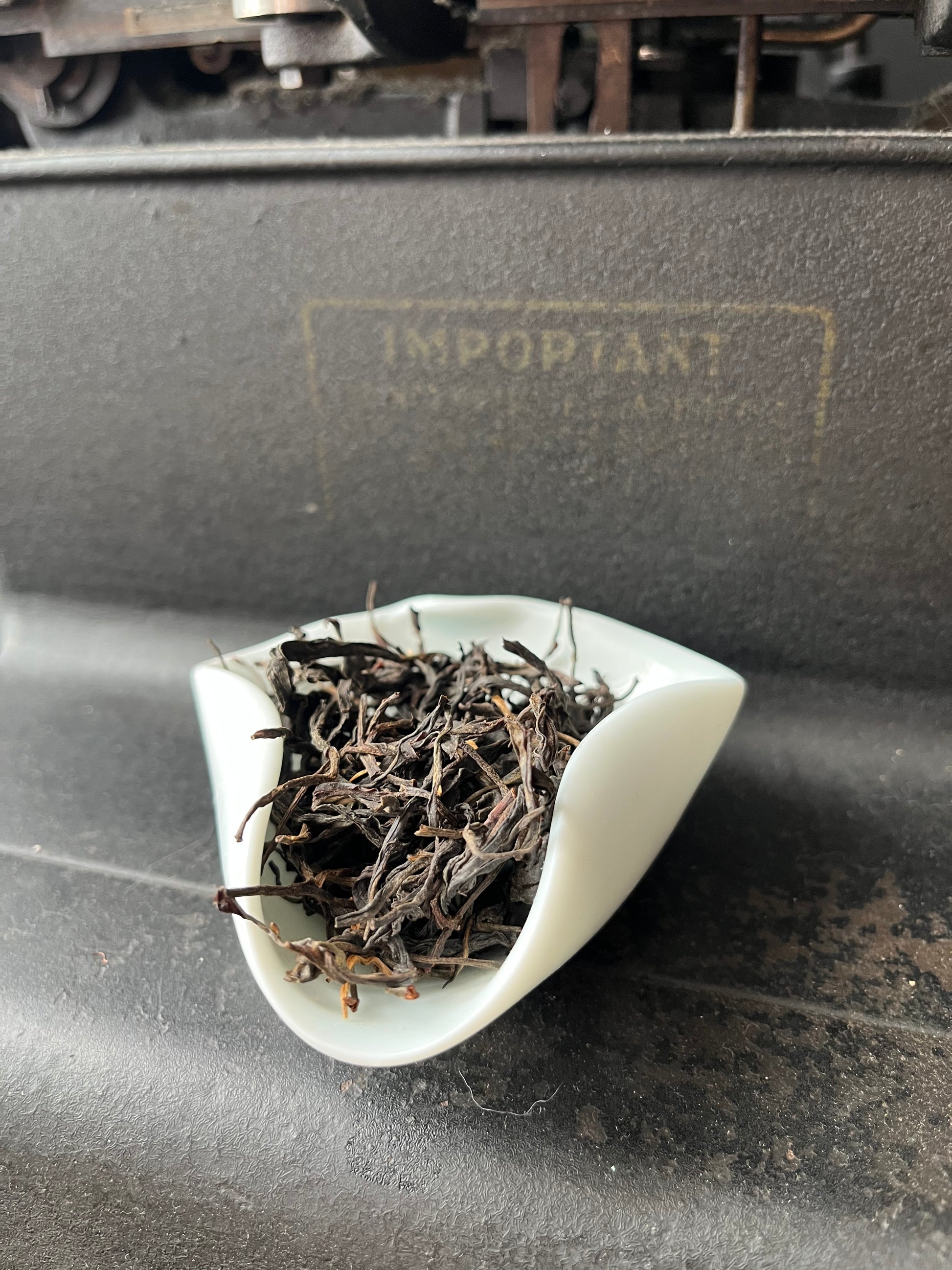 Dried black tea leaves inside, attached to a dark surface.
